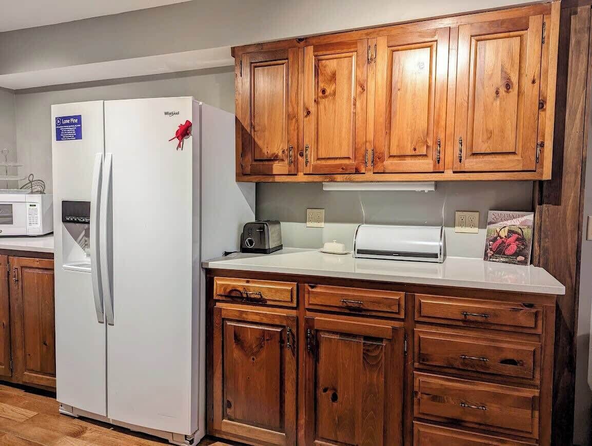 A kitchen with wooden cabinets, a white refrigerator, a microwave, and a toaster.