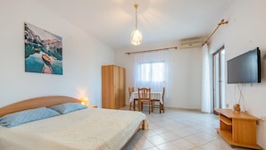Une chambre à coucher avec un lit, un bureau, une chaise, un téléviseur et un tableau représentant un lac.