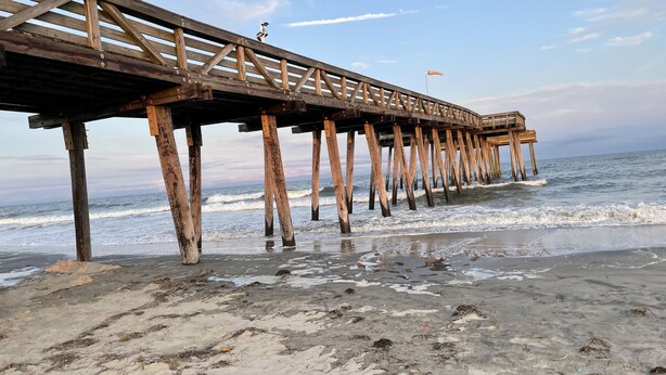 A wooden pier extending into the ocean with a flag on top. - Ocean City, NJ - Feet to the Boardwalk, New Listing, Turnkey & Clean! (Ocean City)