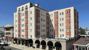 A multi-story hotel with a classic architectural design, featuring a central courtyard with arched walkways and a small outdoor seating area. - Ocean City, NJ - Feet to the Boardwalk, New Listing, Turnkey & Clean! (Ocean City)