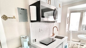 A compact kitchen with white cabinets, a microwave, a coffee maker, and a small sink. - Ocean City, NJ - Feet to the Boardwalk, New Listing, Turnkey & Clean! (Ocean City)
