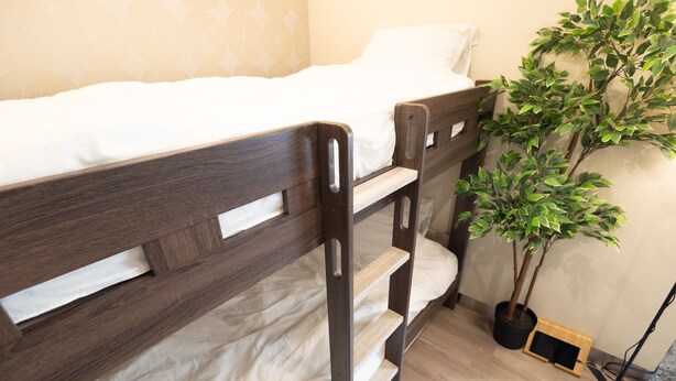 Un lit superposé avec une structure en bois et du linge de lit blanc.