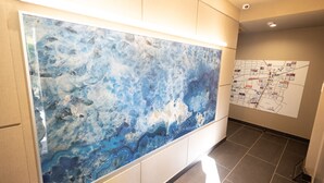 Een hal met een groot abstract kunstwerk aan de muur en een kaart op de aangrenzende muur.
