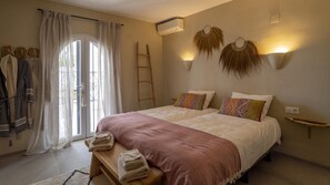 Un dormitorio con dos camas, un banco con toallas, una escalera y luces en la pared.