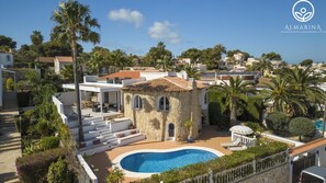 Una villa mediterránea con piscina, arquitectura de piedra y exuberante vegetación.