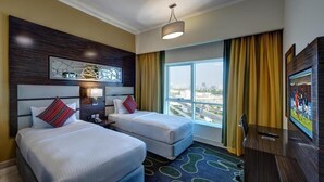 Ein Hotelzimmer mit zwei Betten, einem großen Fenster mit Vorhängen, einem Fernseher und Blick auf die Stadt.