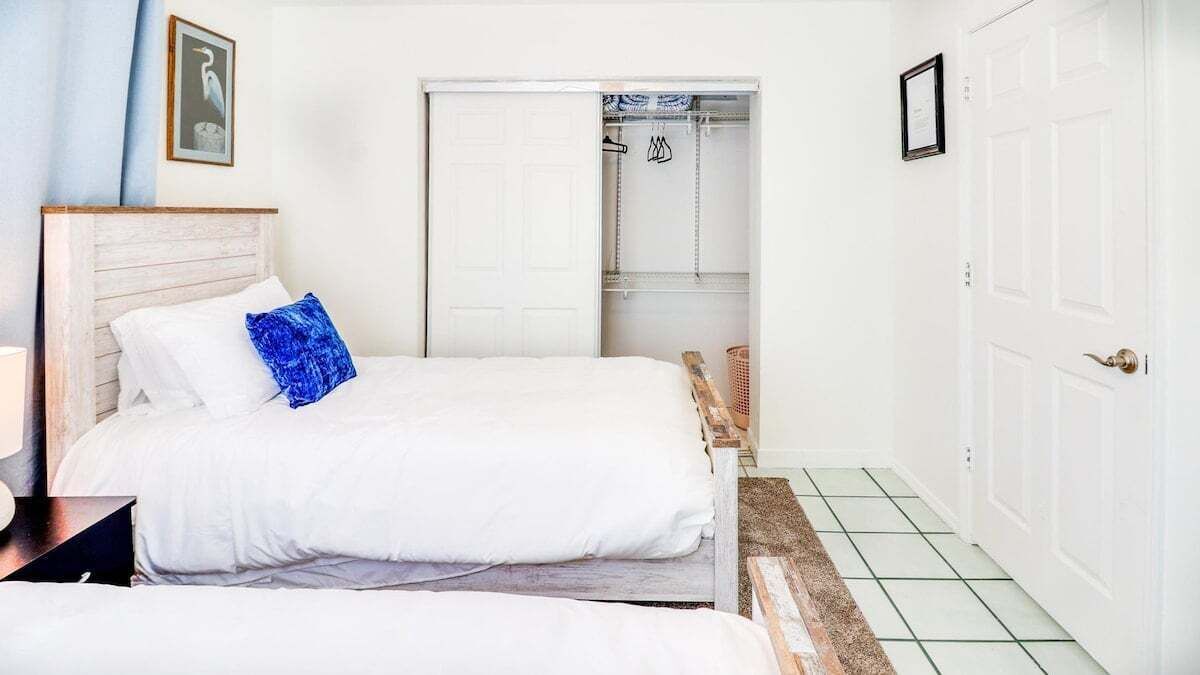 A bedroom with two beds, a wardrobe, and a door leading to a bathroom.