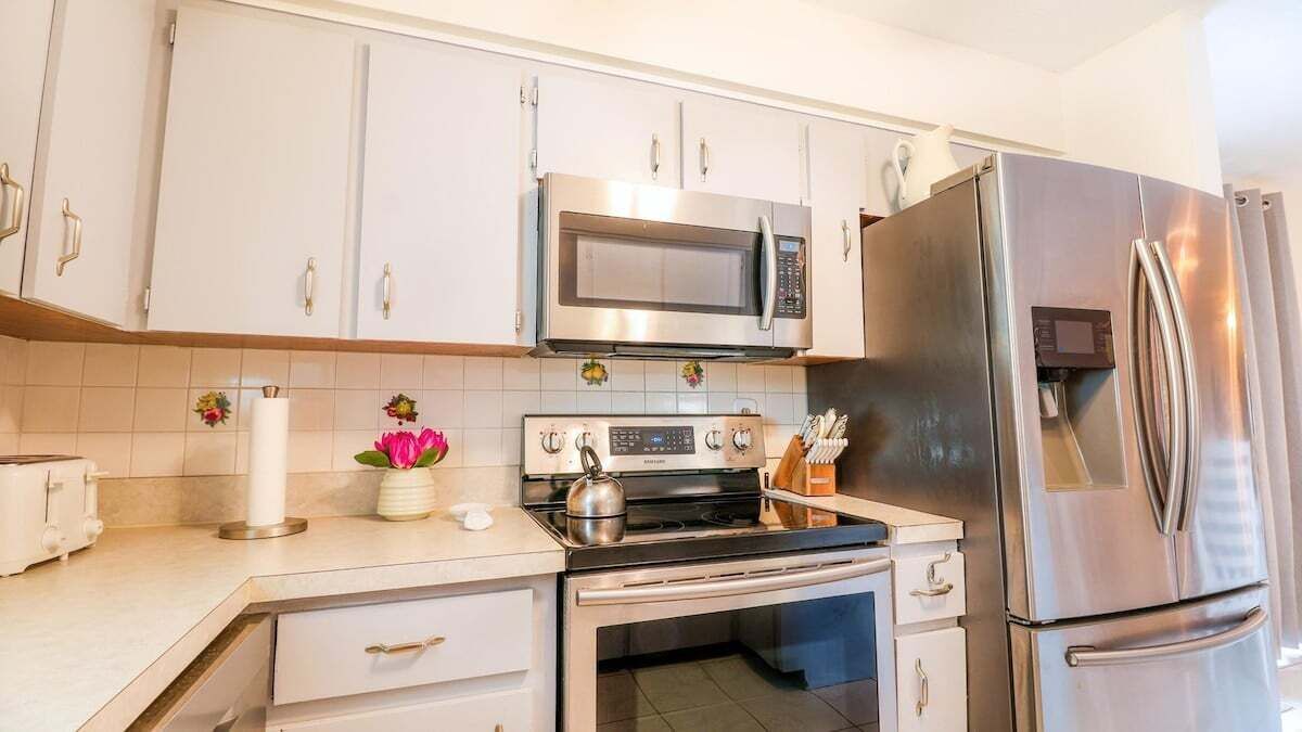 Eine moderne Küche mit weißen Schränken, Edelstahlgeräten, einem Wasserkocher und einem Toaster.