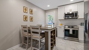 A modern kitchen with white cabinetry, a built-in microwave, a stainless steel oven, and a marble floor. - Modern 3BR Home Near LakePoint with Fenced Yard (Cartersville)