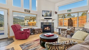A spacious living room with a fireplace, comfortable seating, and large windows offering a scenic view.