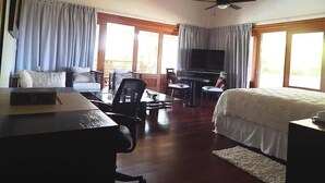 Ein Hotelzimmer mit Bett, Schreibtisch, Fernseher und einem Balkon mit Blick.