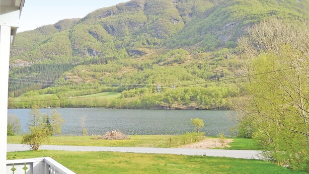 A view of a lake surrounded by mountains, with a road and a fence in the foreground. - Amazing home in Sandeid with lake view (Sandeid)