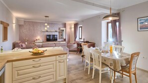 Un salon moderne comprenant un téléviseur, un canapé et un coin repas avec des chaises et une table.