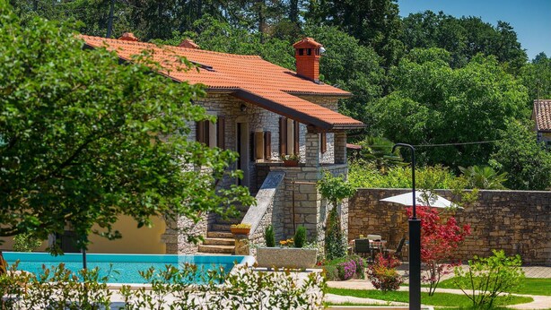 Un bâtiment en pierre avec un toit recouvert de tuiles rouges, un escalier en pierre et une piscine.