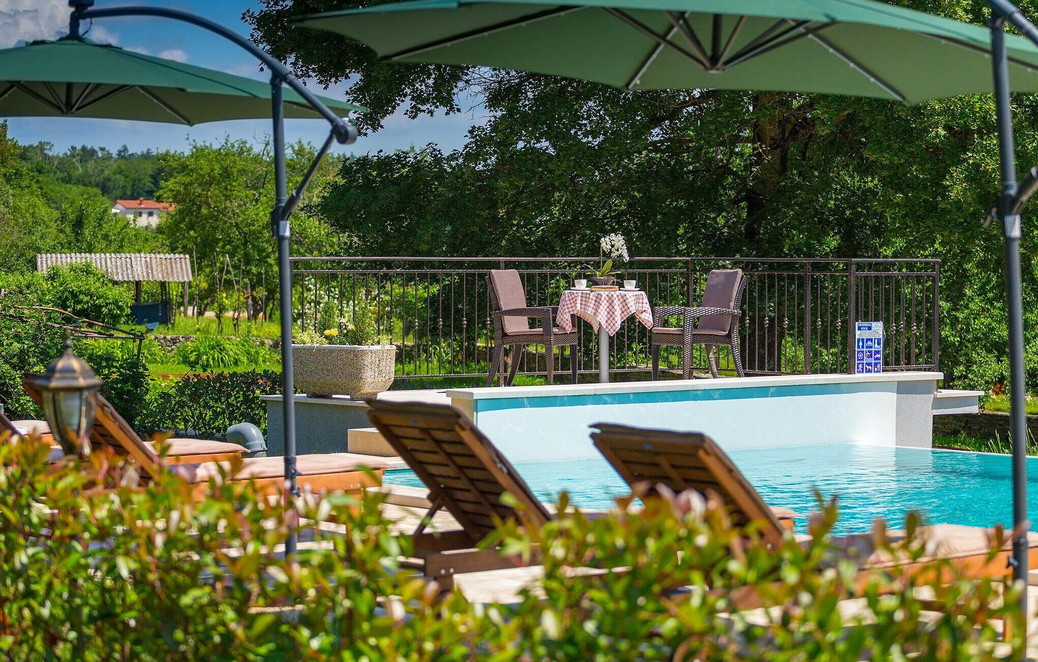 A poolside area with lounge chairs, a table with a checkered tablecloth, and a view of the sea.