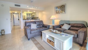 A living room with two grey sofas, a white coffee table, and a kitchen in the background. - Beachfront Views from 2nd and 3rd Floor Balconies (St. Augustine Beach)