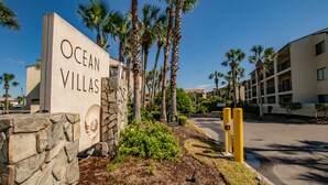 A sign for Ocean Villas with a stone wall and palm trees. - Beachfront Views from 2nd and 3rd Floor Balconies (St. Augustine Beach)