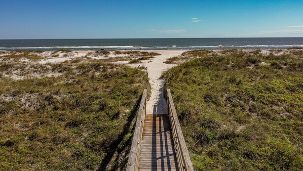 A wooden boardwalk leading to a beach with dunes and ocean in the background. - Beachfront Views from 2nd and 3rd Floor Balconies (St. Augustine Beach)