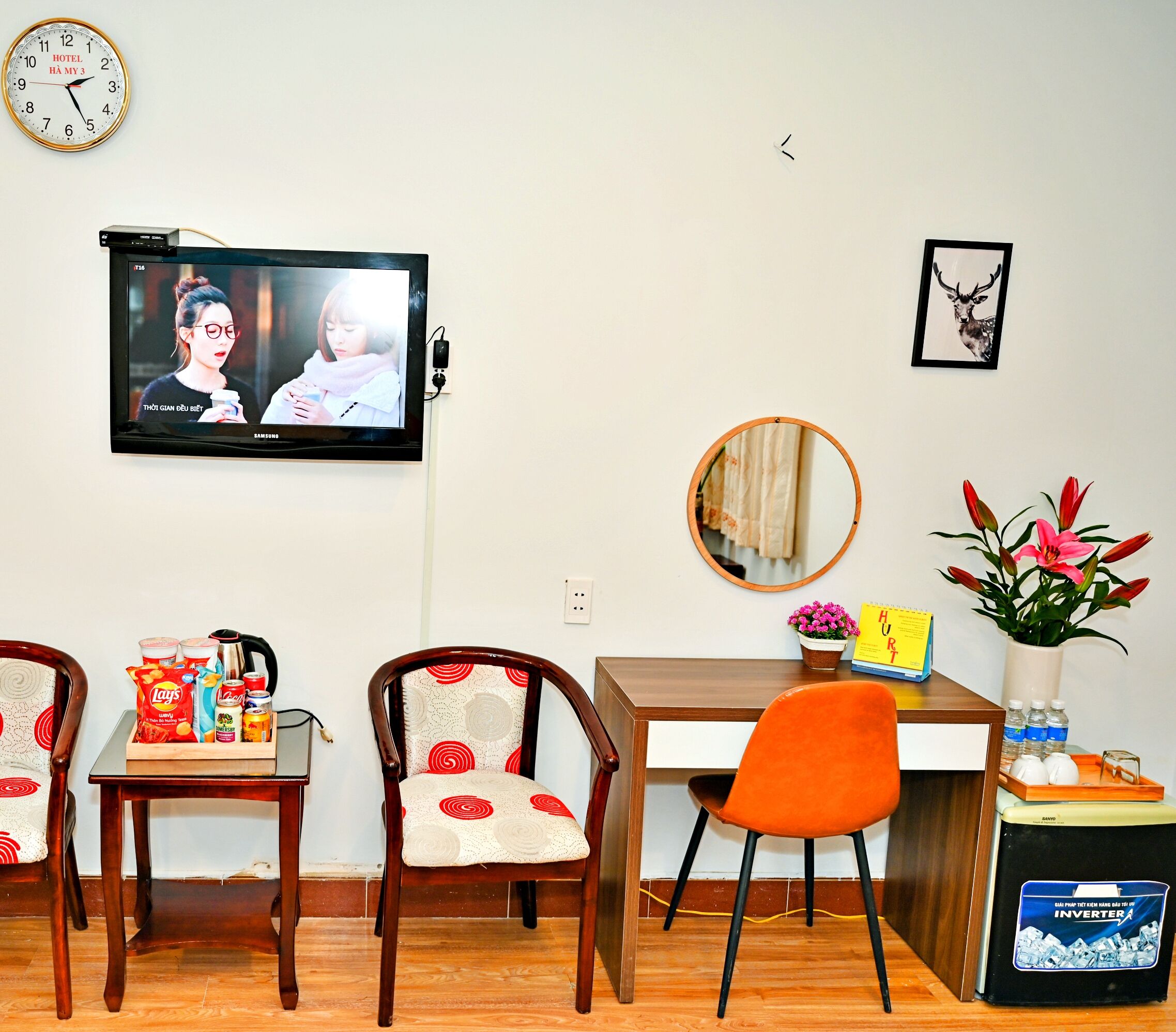 A dining area with a television, chairs, a table, and a small plant.