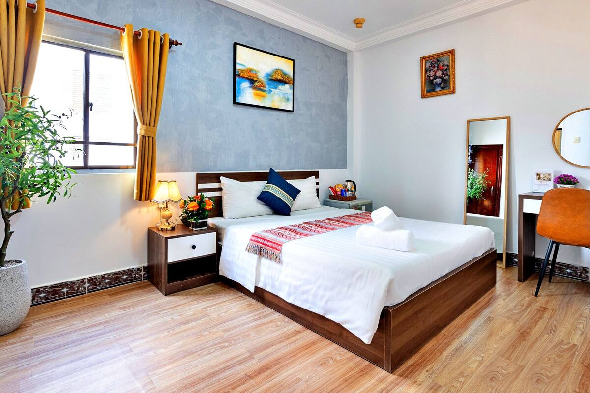 Ein Hotelzimmer mit Bett, Nachttisch, Lampe und einer Zimmerpflanze.