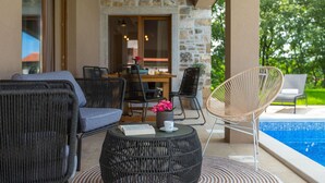 Un espace patio aménagé avec des meubles en osier, une table à manger et une vue sur une piscine.