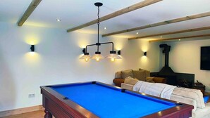 A pool table in a room with wooden beams, a sofa, and a fireplace. - The Stables at Historic Grade ll Listed Farm (Broadstairs)