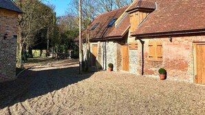 A rural property with a gravel driveway, wooden fences, and a brick building with a sloped roof. - The Stables at Historic Grade ll Listed Farm (Broadstairs)