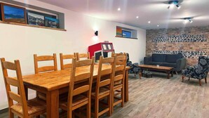 A dining area with a wooden table and chairs, a red microwave, a sofa, and a patterned armchair. - The Stables at Historic Grade ll Listed Farm (Broadstairs)
