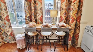 A dining area with a window view, patterned curtains, a stove, and a table set for four. - Overlooks Riverwalk/King/Downtown (San Antonio)