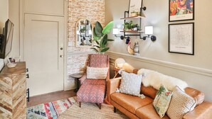 A cozy living room with a herringbone-patterned floor, a leather sofa, a patterned armchair, and a large mirror. - Overlooks Riverwalk/King/Downtown (San Antonio)