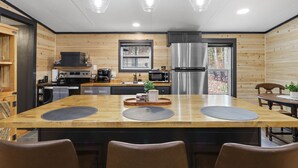 Une cuisine moderne dotée d’un îlot central, d’appareils électroménagers en acier inoxydable et de panneaux muraux en bois.