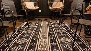 L’intérieur d’une cabane, avec deux fauteuils suspendus, un tapis à motifs et une pancarte indiquant « Bienvenue dans notre cabane ».