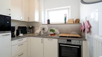 A modern kitchen with white cabinets, a black coffee maker, a Siemens oven, and a window with a view of the outside.