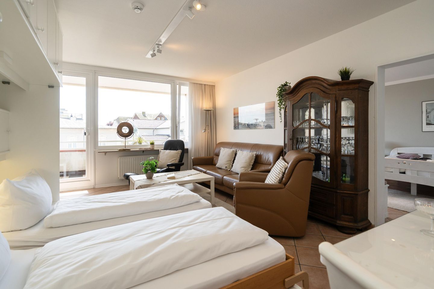 A hotel room with two beds, a sofa, a dining table, and a cabinet.