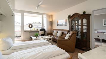 A hotel room with two beds, a sofa, a dining table, and a cabinet.