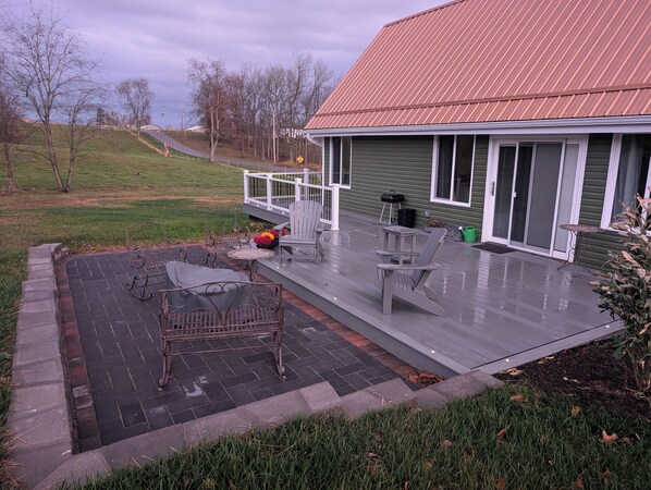 A covered patio area with outdoor furniture, a green house, and a view of the surrounding landscape. - Cozy cottage located in rural Central Ohio. (Utica)