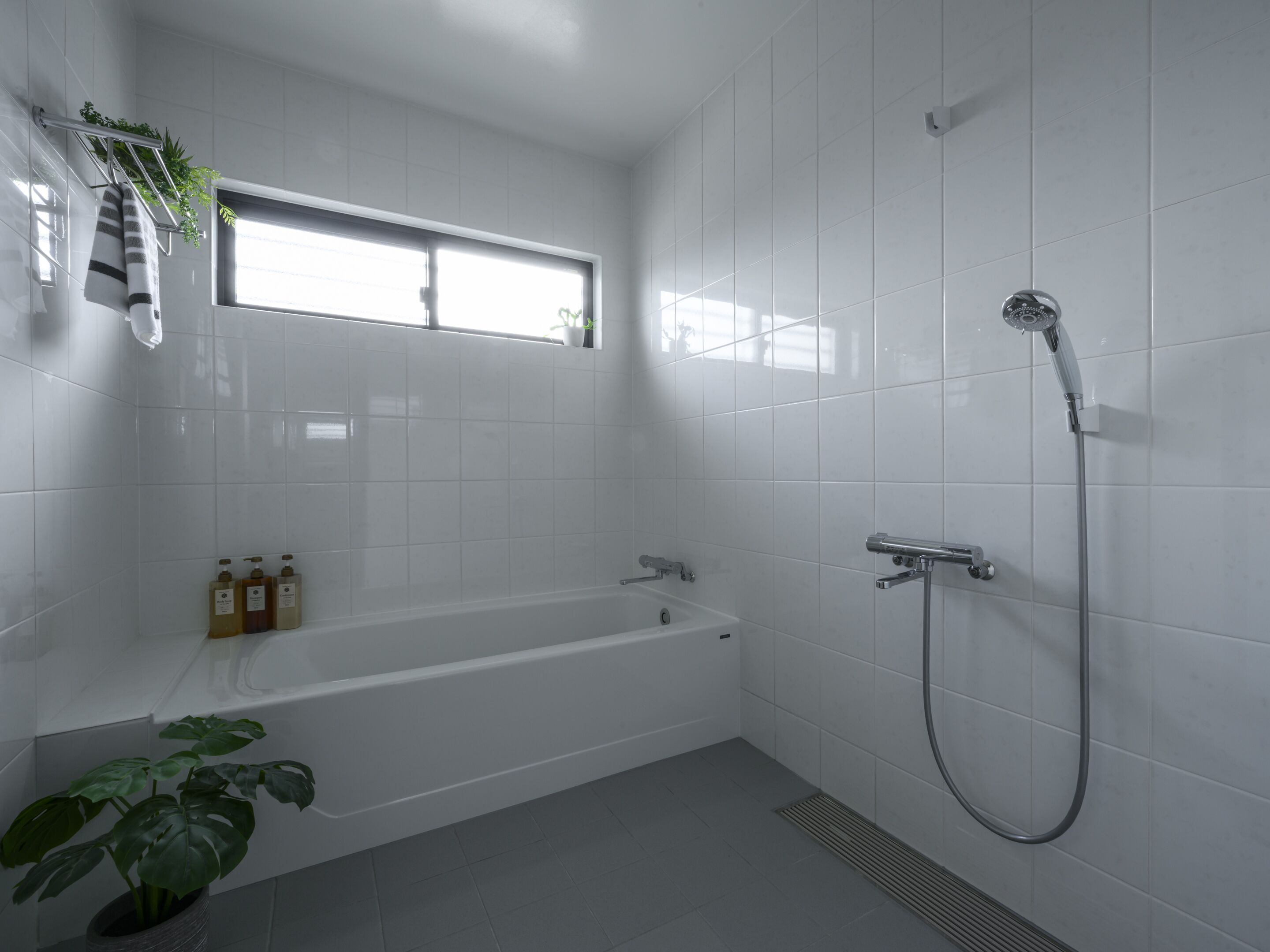 A modern bathroom with a bathtub, shower, and a window providing natural light.