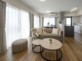 Una sala de estar moderna con un sofá, un reposapiés y dos mesas redondas.