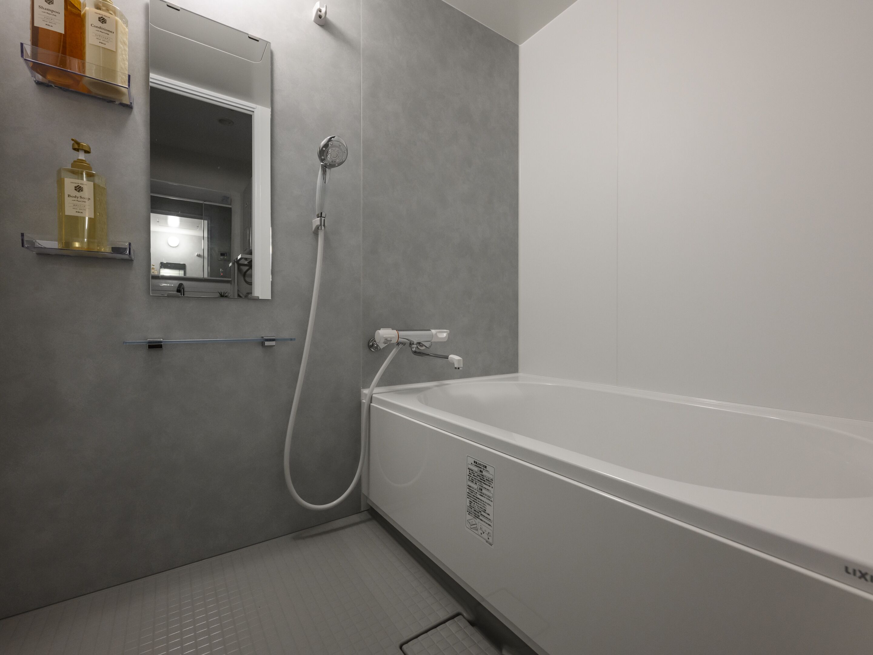 A modern bathroom with a bathtub, a shower, and a mirror.