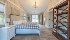 Une chambre à coucher avec un grand lit, une table de chevet, une commode, une bibliothèque en bois et un lustre.