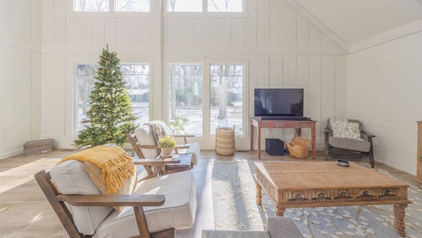 Un loft spacieux avec de hauts plafonds, de grandes fenêtres, un plancher en bois, un coin salon confortable avec une table basse et un téléviseur.