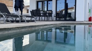 Um edifício moderno com piscina, área de estar externa e vista para o mar.