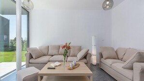 Un salon moderne avec un ensemble de canapés beige, une table basse en bois et un vase rempli de fleurs.