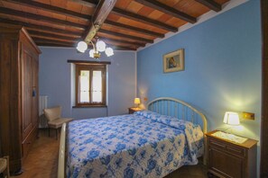 Un dormitorio con una cama, una mesita de noche, una silla, un ventanal y techo de madera.