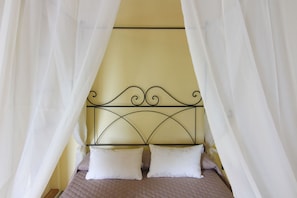 Una cama con dosel, dos almohadas y un cabecero con diseño decorativo.