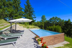 Una piscina con sillones de descanso y una terraza de madera.
