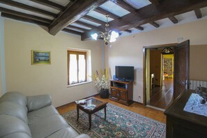 A living room with a sofa, a coffee table, a TV, and a window with curtains.