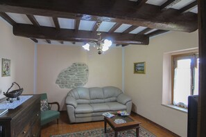 Una sala de estar con pared de piedra, un sofá, una mesa de centro de madera y una araña.