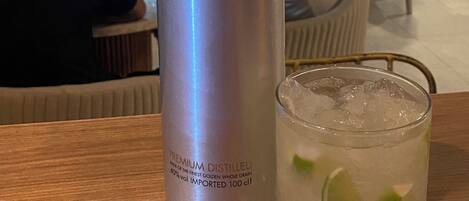 Eine Flasche DANZKA Wodka und ein Glas mit Eiswürfeln und Limette auf einem Holztisch in einem Restaurant.