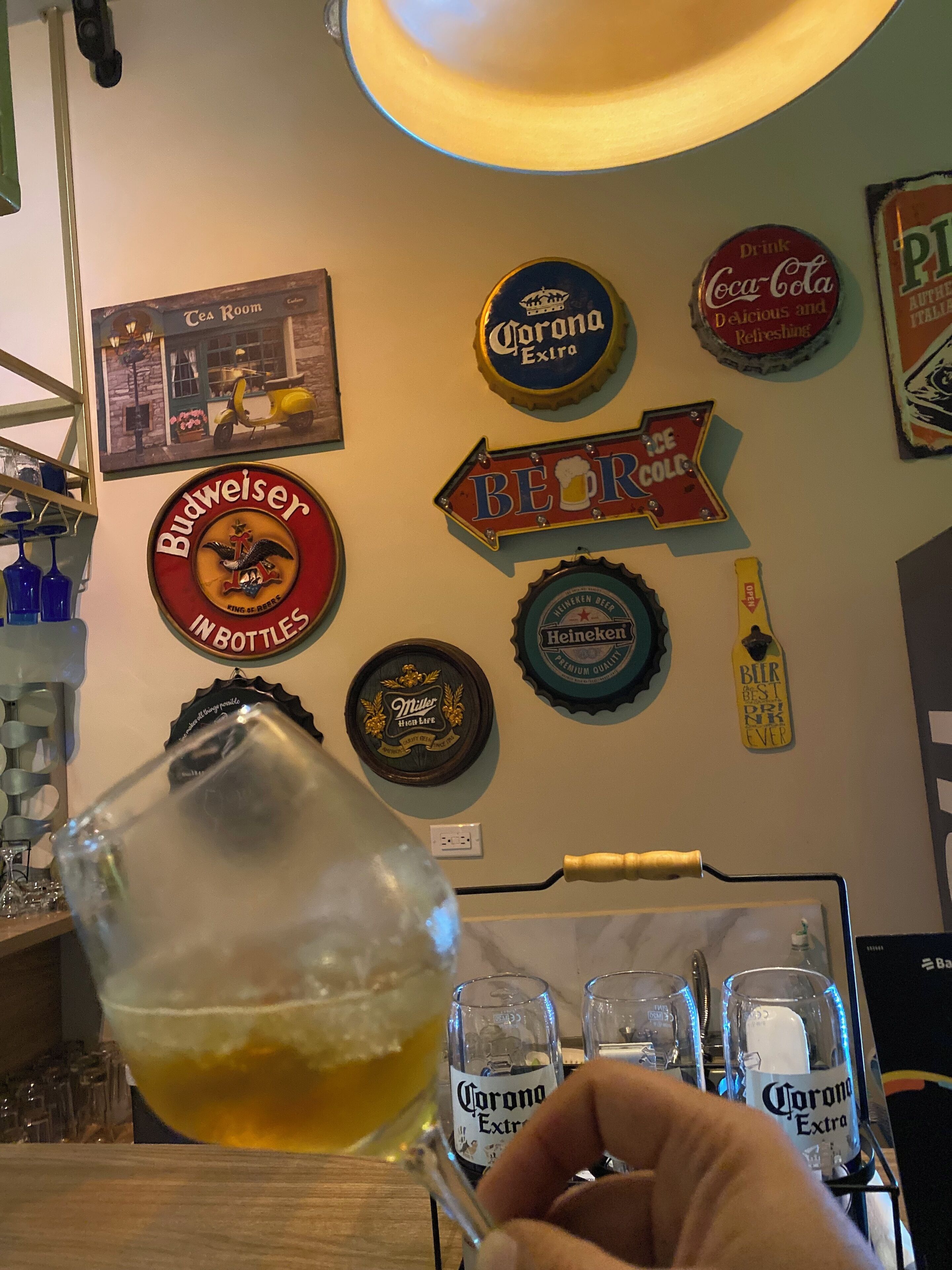 A wall with various beer bottle caps and a glass of beer.
